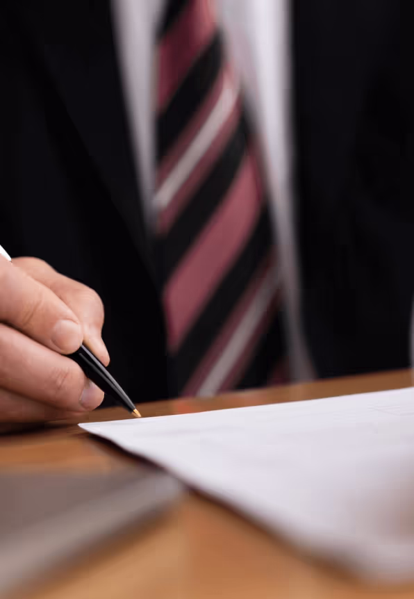 A lawyer uses a pen to sign a document of some kind